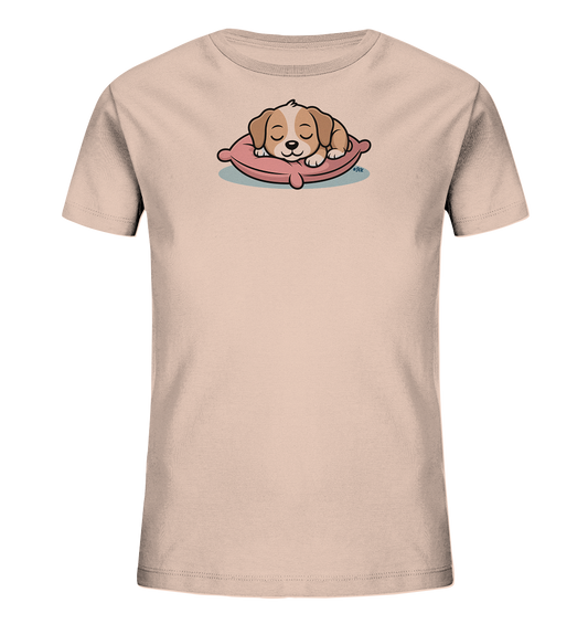 Onlineshop Shirts fuer Kinder - Das Bild zeigt ein hellbeiges Kinder-T-Shirt mit einem niedlichen Tiermotiv auf der Vorderseite. Ein kleiner, braun-weisser Welpe schlaeft friedlich auf einem rosafarbenen Kissen. Das Design wirkt beruhigend und liebevoll, mit klaren Linien und sanften Farben. Es ist ein verspieltes und kinderfreundliches Motiv.