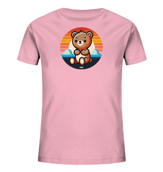 Onlineshop Shirts fuer Kinder - Das Bild zeigt ein hellrosa T-Shirt mit einem runden Aufdruck auf der Vorderseite. Der Aufdruck zeigt einen sitzenden, cartoonhaften Baeren vor einer Landschaft mit Sonnenuntergang, Wasser und Wolken. Der Baer ist braun und hat einen freundlichen Gesichtsausdruck. Das Design ist farbenfroh und niedlich.