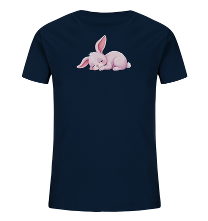 Onlineshop Shirts fuer Kinder - Das Bild zeigt ein dunkelblaues T-Shirt fuer Kinder. Auf der Vorderseite ist eine niedliche Illustration eines schlafenden rosa Hasen zu sehen. Der Hase liegt zusammengerollt mit geschlossenen Augen und langen Ohren. Das Design wirkt ruhig und ansprechend fuer Kinder.