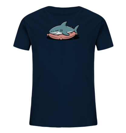 Onlineshop Shirts fuer Kinder - Das Bild zeigt ein dunkelblaues Kinder-T-Shirt. Auf der Vorderseite ist eine niedliche Illustration eines hellblauen Hais zu sehen, der friedlich auf einem rosafarbenen Kissen schlaeft. Das Design wirkt beruhigend und verspielt.