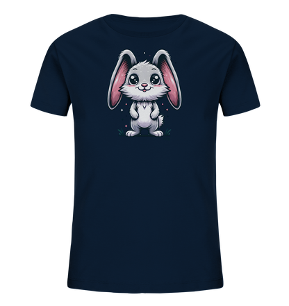 Onlineshop Shirts fuer Kinder - Das Bild zeigt ein dunkelblaues Kinder-T-Shirt. Auf der Vorderseite befindet sich eine Illustration eines niedlichen, weissen Kaninchens mit rosa Ohren und grossen, glaenzenden Augen. Das Kaninchen steht auf einer kleinen gruenen Flaeche mit einigen rosa Glitzerpartikeln im Hintergrund. Das Design wirkt freundlich und verspielt.
