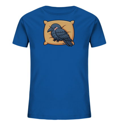 Onlineshop Shirts fuer Kinder - Das Bild zeigt ein leuchtend blaues Kinder-T-Shirt. Auf der Vorderseite ist eine dunkelgraue Cartoon-Kraehe abgebildet, die friedlich auf einem beigefarbenen Kissen schlaeft. Der Vogel hat die Augen geschlossen und eine leichte Roete auf der Wange. Das gesamte Design vermittelt eine ruhige und niedliche Atmosphaere.