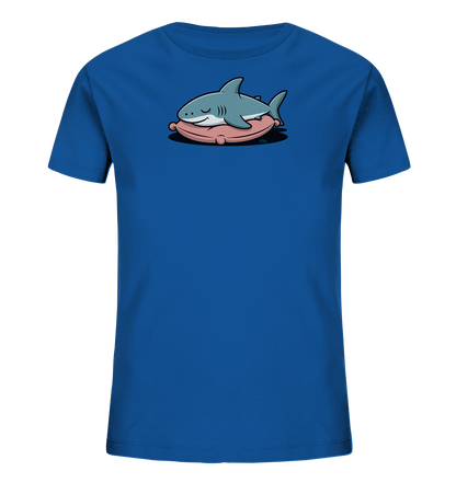 Onlineshop Shirts fuer Kinder - Das Bild zeigt ein leuchtend blaues Kinder-T-Shirt. Auf der Vorderseite ist ein schlafender, hellblauer Cartoon-Hai zu sehen. Der Hai liegt friedlich auf einem rosafarbenen Kissen. Dieses niedliche Design wirkt beruhigend und verspielt.