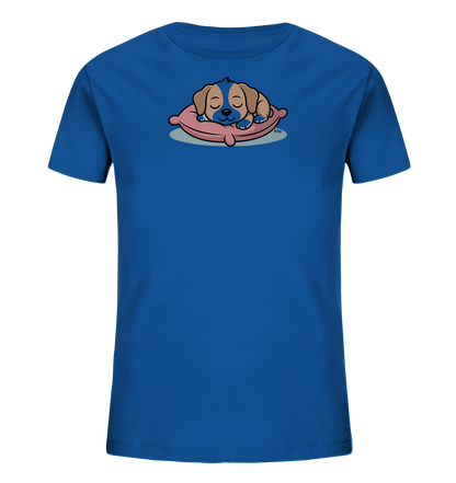 Onlineshop Shirts fuer Kinder - Das Bild zeigt ein blaues Kinder-T-Shirt mit einem niedlichen Tiermotiv auf der Vorderseite. Abgebildet ist ein kleiner, schlafender Welpe mit braunem und blauem Fell, der gemuetlich auf einem rosa Kissen liegt. Der Welpe hat geschlossene Augen und wirkt sehr friedlich. Das Design verleiht dem Shirt einen ruhigen und verspielten Charakter.