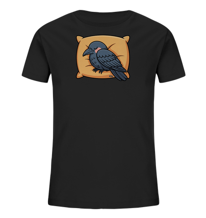 Onlineshop Shirts fuer Kinder - Das Bild zeigt ein schwarzes Kinder-T-Shirt mit einem niedlichen Motiv eines schlafenden Raben. Der Rabe liegt gemuetlich auf einem orangefarbenen Kissen, die Augen geschlossen und leichte rote Wangen. Das Design wirkt beruhigend und ist ideal fuer Kinder.