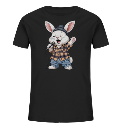 Onlineshop Shirts fuer Kinder - Das Bild zeigt ein schwarzes Kinder-T-Shirt mit einem niedlichen Comic-Hasen auf der Vorderseite. Der Hase traegt eine Muetze, ein kariertes Hemd und Jeans und haelt ein Mikrofon. Er scheint froehlich zu singen oder zu performen, mit offenem Mund und erhobener Pfote. Das Design wirkt verspielt und lebendig.