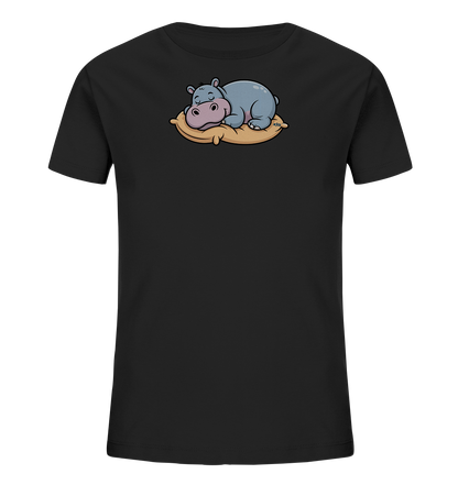 Onlineshop Shirts fuer Kinder - Das Bild zeigt ein schwarzes T-Shirt fuer Kinder. Auf der Vorderseite ist ein niedliches, schlafendes Nilpferd abgebildet, das auf einem beigefarbenen Kissen liegt. Das Nilpferd ist in einem sanften Grau-Blau gehalten und hat eine rosa Schnauze. Das verspielte Design verleiht dem Shirt einen gemuetlichen und freundlichen Charakter.