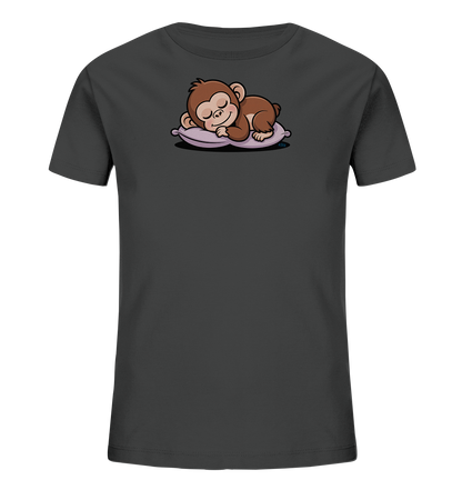 Onlineshop Shirts fuer Kinder - Das Bild zeigt ein dunkelgraues Kinder-T-Shirt mit einem niedlichen Frontdruck. Auf der Vorderseite ist ein schlafender, brauner Affe abgebildet, der friedlich auf einem lilafarbenen Kissen liegt. Der Affe hat die Augen geschlossen und ein sanftes Laecheln, was dem Design eine ruhige und liebevolle Ausstrahlung verleiht. Die Illustration ist in einem charmanten Cartoon-Stil gehalten.