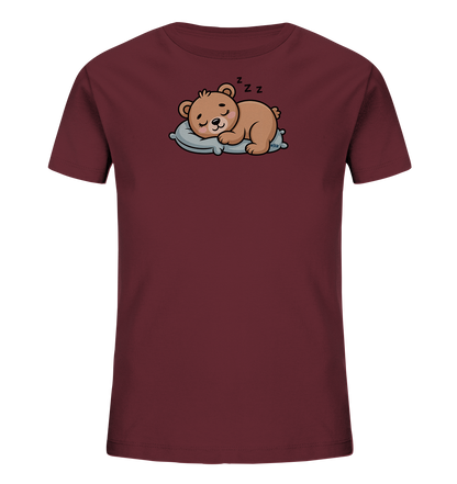 Onlineshop Shirts fuer Kinder - Das Bild zeigt ein dunkelrotes Kinder-T-Shirt mit einem niedlichen Aufdruck. Ein brauner Cartoon-Baer schlaeft friedlich auf einem hellblauen Kissen. Über seinem Kopf sind "ZzZ"-Symbole zu sehen, die seinen Schlaf andeuten. Das Design wirkt beruhigend und ist ideal fuer kleine Kinder.