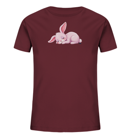 Onlineshop Shirts fuer Kinder - Das Bild zeigt ein dunkelrotes Kinder-T-Shirt. Auf der Vorderseite ist eine niedliche, schlafende Hasenillustration zu sehen. Das Haeschen ist rosa, liegt zusammengerollt und hat die Augen geschlossen, was einen friedlichen Ausdruck vermittelt. Die gesamte Gestaltung wirkt sanft und kinderfreundlich.