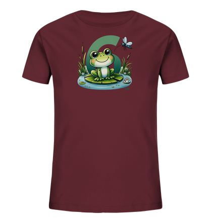 Onlineshop Shirts fuer Kinder - Das Bild zeigt ein dunkelrotes T-Shirt fuer Kinder mit einem farbigen Motiv auf der Vorderseite. Abgebildet ist ein laechelnder Frosch, der auf einem Seerosenblatt in einem Teich sitzt. Er ist umgeben von Schilf, einer Seerose und einer Libelle. Im Hintergrund ist eine grosse gruene Zahl '6' zu sehen, was dem Design einen verspielten Charakter verleiht.