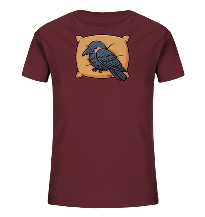 Onlineshop Shirts fuer Kinder - Das Bild zeigt ein bordeauxrotes Kinder-T-Shirt. Auf der Vorderseite ist ein schlafender, dunkelgrauer Vogel auf einem beigen Kissen abgebildet. Der Vogel wirkt friedlich und suess mit seinen geschlossenen Augen und roten Wangen. Das Design verleiht dem Shirt einen gemuetlichen Charakter.