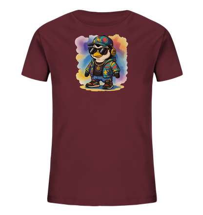 Onlineshop Shirts fuer Kinder - Das Bild zeigt ein bordeauxrotes Kinder-T-Shirt mit einem farbenfrohen Motiv auf der Vorderseite. Es ist ein cartoonhafter Pinguin abgebildet, der eine trendige Hip-Hop-Kleidung mit Sonnenbrille, Kopfhoerern, Kappe und einer bunten Jacke traegt. Hinter dem Pinguin befindet sich ein bunter Aquarell-Hintergrund, der das Design lebendig wirken laesst. Die Gestaltung ist verspielt und modern.