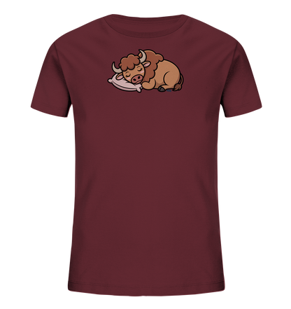 Onlineshop Shirts fuer Kinder - Das Bild zeigt ein bordeauxrotes Kinder-T-Shirt. Auf der Vorderseite ist eine niedliche, cartoonartige Illustration eines schlafenden Bueffels zu sehen. Das Tier liegt friedlich auf einem hellrosa Kissen, die Augen geschlossen. Das Design wirkt ruhig und ansprechend.