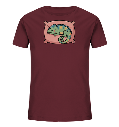 Onlineshop Shirts fuer Kinder - Das Bild zeigt ein dunkelrotes T-Shirt fuer Kinder. Es ist mit einer Illustration eines schlafenden Chamaeleons verziert, das auf einem rosafarbenen Kissen liegt. Das Chamaeleon ist in Gruentoenen mit blauen und gelben Akzenten gehalten. Das Design wirkt beruhigend und verspielt.