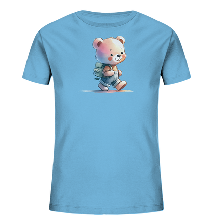 Onlineshop Shirts für Kinder - Das Bild zeigt ein hellblaues T-Shirt mit einem niedlichen Aufdruck auf der Vorderseite. Das Motiv stellt einen kleinen Cartoon-Bären dar, der Overalls und einen Rucksack trägt und gerade läuft. Der Bär hat einen fröhlichen Gesichtsausdruck und ist in sanften Farben gestaltet. Das Design ist kindgerecht und ansprechend.