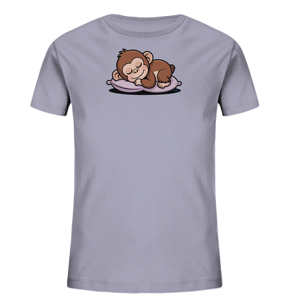 Onlineshop Shirts fuer Kinder - Das Bild zeigt ein hellgraues T-Shirt fuer Kinder. Auf der Vorderseite befindet sich eine detaillierte Illustration eines braunen Affen, der schlafend auf einem lilafarbenen Kissen liegt. Der Affe ist mit geschlossenen Augen und einer entspannten Haltung dargestellt. Das Motiv verleiht dem Shirt einen ruhigen und niedlichen Charakter.