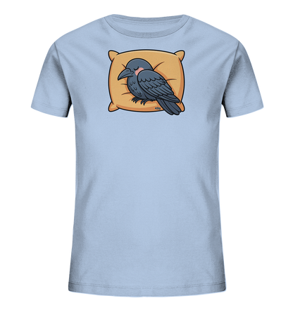 Onlineshop Shirts fuer Kinder - Das Bild zeigt ein hellblaues Kinder-T-Shirt mit einem niedlichen Aufdruck. Dieser zeigt einen dunkelgrauen Vogel, der an einen Raben erinnert, friedlich auf einem orangefarbenen Kissen schlafend. Der Vogel hat geschlossene Augen und leicht rosige Wangen, was einen ruhigen und sanften Ausdruck schafft. Das Motiv verleiht dem T-Shirt einen verspielten Charakter.