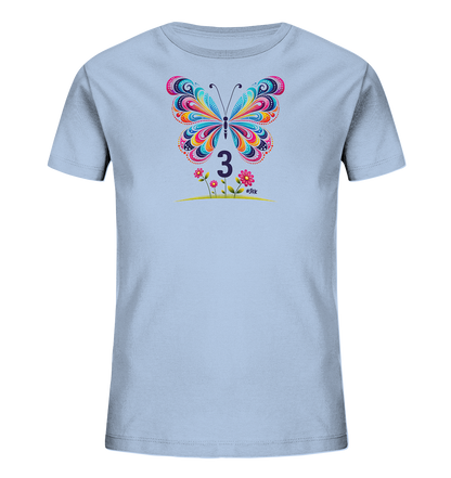 Onlineshop Shirts fuer Kinder - Das Bild zeigt ein hellblaues T-Shirt fuer Kinder. Auf der Vorderseite ist ein grossflaechiger, bunter Schmetterling abgebildet, dessen Fluegel mit ornamentalen Mustern verziert sind. Unter dem Schmetterling steht die Zahl '3' in einem dunklen Farbton, umgeben von einer kleinen Illustration mit rosa Blumen und gruenen Grashalmen. Das gesamte Design wirkt sehr farbenfroh und froehlich, ideal fuer junge Traeger.
