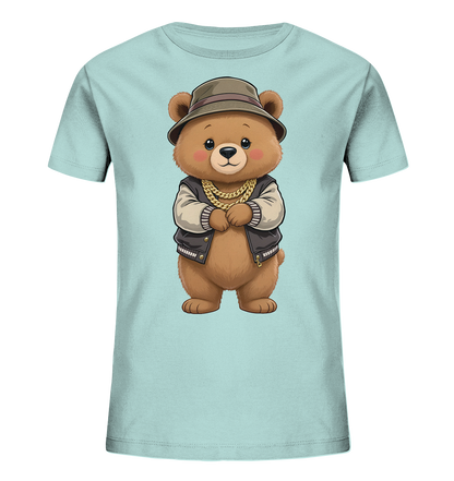 Onlineshop Shirts fuer Kinder - Das Bild zeigt ein hellblaues Kinder-T-Shirt mit einem niedlichen Cartoon-Baerenmotiv auf der Vorderseite. Der Baer ist braun, traegt einen braunen Hut, eine Bomberjacke und eine auffaellige goldene Kette. Er steht mit verschraenkten Armen da und hat ein freundliches Gesicht mit grossen Augen und roten Wangen. Das Design verleiht dem Shirt einen verspielten und gleichzeitig laessigen Charakter.