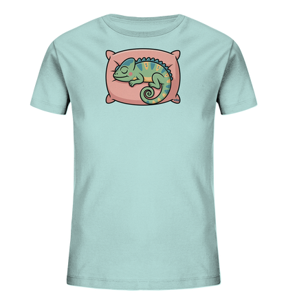 Onlineshop Shirts fuer Kinder - Das Bild praesentiert ein hellblaues T-Shirt fuer Kinder. Auf der Vorderseite ist eine liebevolle Illustration eines schlafenden Chamaeleons zu sehen. Das gruene Chamaeleon liegt entspannt auf einem rosa Kissen, was dem Motiv eine ruhige und friedliche Ausstrahlung verleiht. Die Gestaltung ist verspielt und farbenfroh.