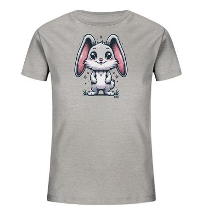 Onlineshop Shirts fuer Kinder - Das Bild zeigt ein graues Kinder-T-Shirt mit einem niedlichen Comic-Hasen. Der Hase ist weiss/grau mit grossen rosa Ohren und einem freundlichen Laecheln. Er steht auf einer kleinen Grasflaeche, umgeben von funkelnden Sternen. Das Design ist kindgerecht und verspielt gestaltet.
