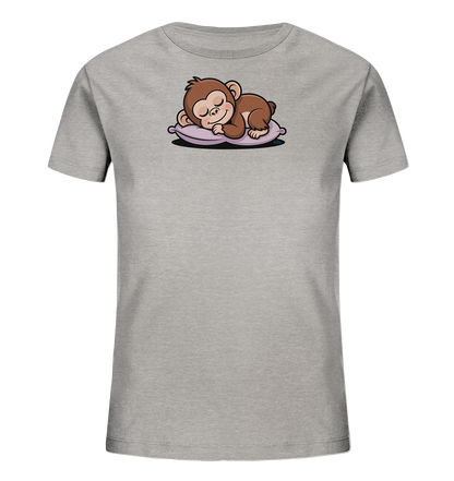 Onlineshop Shirts fuer Kinder - Das Bild zeigt ein hellgraues T-Shirt fuer Kinder. Im oberen Bereich der Vorderseite ist eine Grafik eines schlafenden, braunen Affen zu sehen. Der Affe liegt friedlich auf einem violettfarbenen Kissen, dargestellt in einem freundlichen Cartoon-Stil.