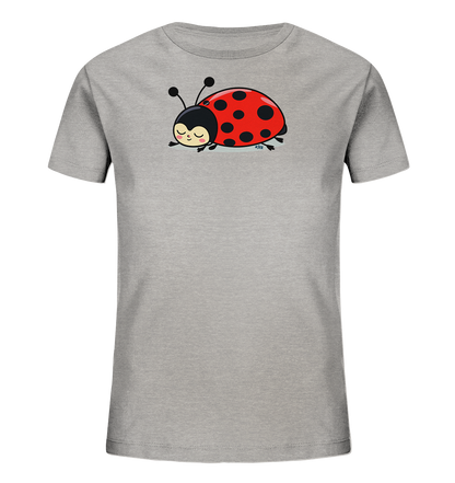 Onlineshop Shirts fuer Kinder - Das Bild zeigt ein hellgraues Kinder-T-Shirt mit einem niedlichen Marienkaefer-Motiv auf der Vorderseite. Der Marienkaefer ist rot mit schwarzen Punkten und hat einen schwarzen Kopf mit Fuehlern. Er liegt schlafend oder ruhend da, mit geschlossenen Augen und einem sanften Laecheln. Dieses Motiv verleiht dem Shirt einen verspielten und friedlichen Charakter.