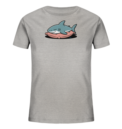Onlineshop Shirts fuer Kinder - Das Bild zeigt ein hellgraues Kinder-T-Shirt. Auf der Vorderseite ist ein cartoonartiger, schlafender Hai abgebildet. Der Hai ist hellblau und liegt gemuetlich mit geschlossenen Augen auf einem rosafarbenen Kissen. Das Motiv wirkt friedlich und verspielt, passend fuer Kinder.