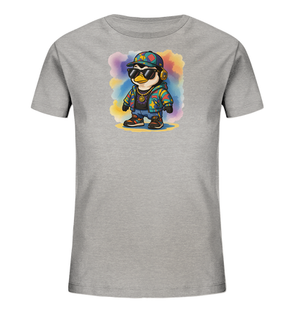 Onlineshop Shirts fuer Kinder - Das Bild zeigt ein hellgraues Kinder-T-Shirt mit einem farbenfrohen Motiv. Abgebildet ist ein Pinguin in stylischer Kleidung, bestehend aus Sonnenbrille, Muetze, Kopfhoerern, bunter Jacke und Goldkette. Er steht vor einem abstrakten Hintergrund aus bunten Aquarellflecken. Das Design wirkt modern und verspielt.