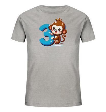 Onlineshop Shirts fuer Kinder - Das Bild zeigt ein hellgraues Kinder-T-Shirt. Auf der Vorderseite ist eine niedliche, cartoonartige Affenfigur abgebildet. Der Affe sitzt neben einer grossen blauen Zahl '3' und scheint diese zu beruehren. Dieses Design wirkt verspielt und ist fuer Kinder ansprechend.