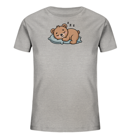 Onlineshop Shirts fuer Kinder - Das Bild zeigt ein graues Kinder-T-Shirt mit einem niedlichen Aufdruck. Ein brauner Cartoon-Baer schlaeft friedlich auf einem hellblauen Kissen, mit 'Zzz'-Symbolen ueber seinem Kopf. Das Design wirkt sehr gemuetlich und kindgerecht, ideal fuer kleine Traeumer.