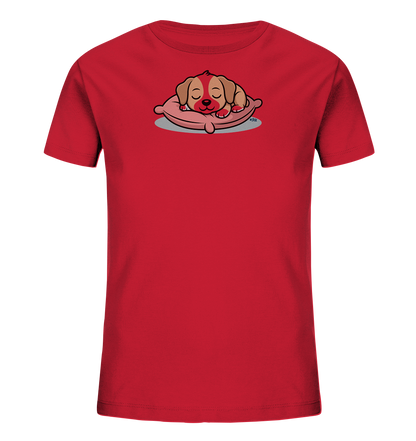 Onlineshop Shirts fuer Kinder - Das Bild zeigt ein rotes Kinder-T-Shirt mit einem niedlichen Aufdruck eines schlafenden Hundewelpen. Der Welpe liegt friedlich auf einem rosafarbenen Kissen, die Augen geschlossen und der Ausdruck ist sanft. Das Design ist in einem charmanten Cartoon-Stil gehalten und wirkt sehr beruhigend. Es ist ein froehliches und ansprechendes Motiv fuer Kinderkleidung.