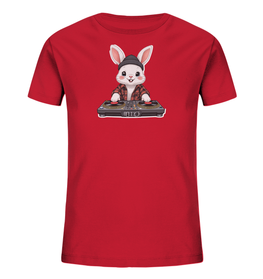 Onlineshop Shirts fuer Kinder - Das Bild zeigt ein rotes Kinder-T-Shirt mit einem niedlichen DJ-Hasen-Motiv auf der Vorderseite. Der Hase traegt eine schwarze Muetze und ein rot-schwarz kariertes Hemd. Er steht hinter einem DJ-Mischpult mit zwei Plattenspielern und hat einen freundlichen Ausdruck. Das Design wirkt verspielt und modern.
