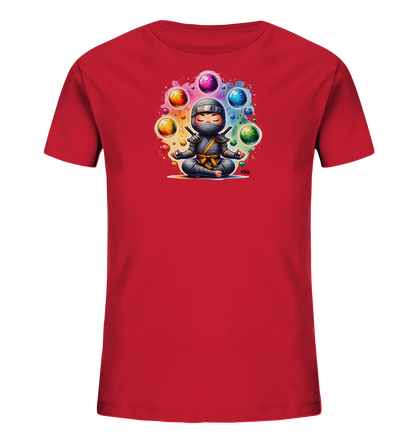 Onlineshop Shirts fuer Kinder - Das Bild zeigt ein rotes T-Shirt fuer Kinder. Auf der Vorderseite ist eine Illustration eines Cartoon-Ninjas zu sehen, der im Lotussitz meditiert. Der Ninja ist von leuchtenden, bunten Kugeln umgeben, die ueber ihm schweben. Das Design strahlt Ruhe und Konzentration aus.