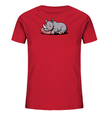 Onlineshop Shirts fuer Kinder - Das Bild zeigt ein leuchtend rotes T-Shirt fuer Kinder. Auf der Vorderseite ist eine suesse, cartoonartige Illustration eines schlafenden Nashorns zu sehen. Das graue Nashorn liegt friedlich auf einem pinkfarbenen Kissen, die Augen geschlossen und ein sanftes Laecheln auf dem Gesicht. Dieses verspielte Design verleiht dem Shirt einen liebenswerten und ruhigen Ausdruck.