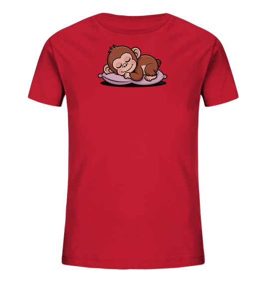 Onlineshop Shirts fuer Kinder - Das Bild zeigt ein rotes Kinder-T-Shirt. Auf der Vorderseite ist ein suesser, brauner Cartoon-Affe abgebildet, der friedlich auf einem lila Kissen schlaeft. Der Affe hat geschlossene Augen und einen entspannten Ausdruck. Das Design verleiht dem Shirt eine beruhigende und niedliche Ausstrahlung.