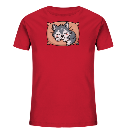 Onlineshop Shirts fuer Kinder - Das Bild zeigt ein leuchtend rotes Kinder-T-Shirt. Im Zentrum der Vorderseite ist ein niedlicher, cartoonhafter Wolfswelpe abgebildet, der friedlich auf einem beigefarbenen Kissen schlaeft. Der Welpe hat ein graues Fell mit weissen Akzenten und geschlossene Augen mit rosafarbenen Wangen. Das Motiv verleiht dem Shirt einen sanften und beruhigenden Charakter.