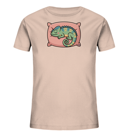 Onlineshop Shirts fuer Kinder - Dieses hellbeige Kinder-T-Shirt praesentiert ein charmantes Motiv eines schlafenden Chamaeleons. Das gruene Chamaeleon mit gelben Akzenten liegt friedlich auf einem rosa Kissen, den Schwanz geringelt. Das liebevolle und ruhige Design verleiht dem Shirt einen verspielten Charakter, perfekt fuer kleine Traeumer.