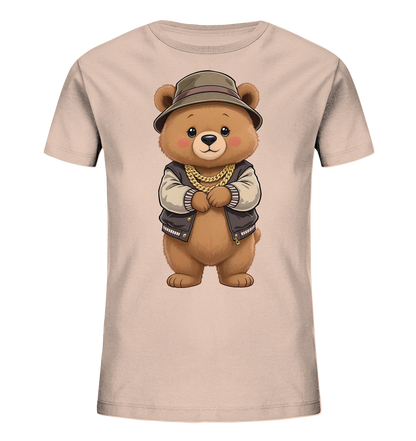 Onlineshop Shirts fuer Kinder - Das Bild zeigt ein hellbeiges Kinder-T-Shirt mit einem niedlichen Baerenmotiv auf der Vorderseite. Der Baer traegt einen olivgruenen Hut, eine braune Bomberjacke mit beigen Ärmeln und eine goldene Kette. Er steht mit verschraenkten Armen da und hat einen freundlichen Ausdruck. Das Design wirkt verspielt und gleichzeitig laessig.