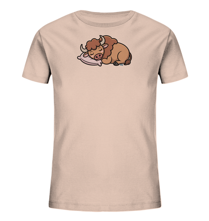 Onlineshop Shirts fuer Kinder - Das Bild praesentiert ein hellbeiges Kinder-T-Shirt, dessen Vorderseite ein suesses, schlafendes Bison-Motiv ziert. Das cartoonartige Bison mit braunem Fell und Hoernern ruht friedlich auf einem rosa Kissen. Die geschlossenen Augen des Tieres verleihen der Illustration einen ruhigen und entspannten Charakter. Dieses verspielte Design ist ansprechend fuer Kinder.