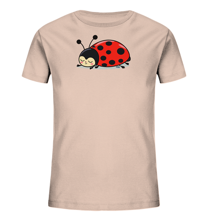Onlineshop Shirts fuer Kinder - Das Bild zeigt ein hellrosa Kinder-T-Shirt mit einem niedlichen Marienkaefer-Motiv auf der Vorderseite. Der Marienkaefer ist rot mit schwarzen Punkten, hat einen schwarzen Kopf mit Fuehlern und ruht in einer entspannten Pose. Sein Gesichtsausdruck ist friedlich und laechelnd, mit geschlossenen Augen. Das Design wirkt verspielt und ist ansprechend fuer Kinder gestaltet.