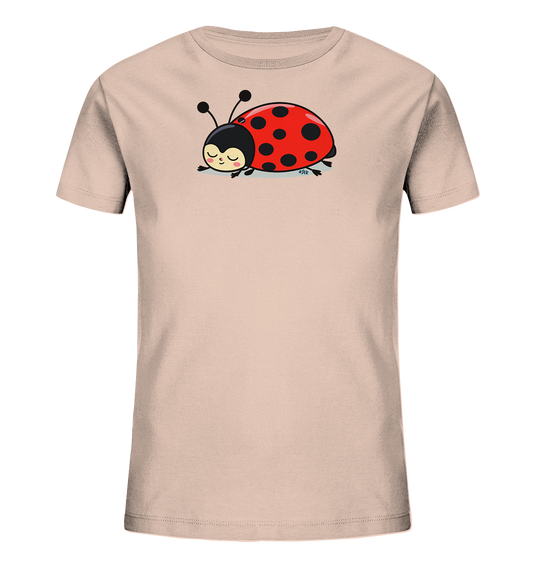 Onlineshop Shirts fuer Kinder - Das Bild zeigt ein hellrosa Kinder-T-Shirt mit einem niedlichen Marienkaefer-Motiv auf der Vorderseite. Der Marienkaefer ist rot mit schwarzen Punkten, hat einen schwarzen Kopf mit Fuehlern und ruht in einer entspannten Pose. Sein Gesichtsausdruck ist friedlich und laechelnd, mit geschlossenen Augen. Das Design wirkt verspielt und ist ansprechend fuer Kinder gestaltet.
