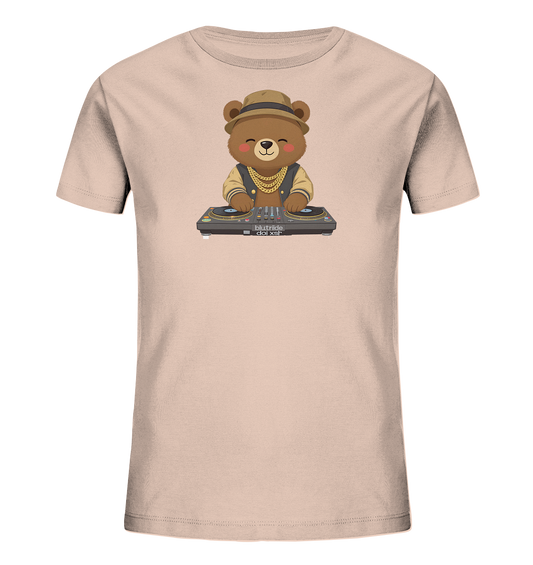 Onlineshop Shirts fuer Kinder - Das Bild zeigt ein hellbeiges Kinder-T-Shirt mit einem niedlichen Cartoon-Baerenmotiv. Der Baer traegt einen Hut, eine goldene Kette und eine Jacke. Er steht laechelnd hinter einem DJ-Mischpult mit zwei Plattenspielern. Das Design verleiht dem Shirt einen verspielten und musikalischen Charakter.