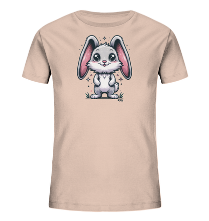 Onlineshop Shirts fuer Kinder - Das Bild zeigt ein hellrosa Kinder-T-Shirt mit einem niedlichen Cartoon-Hasenmotiv auf der Vorderseite. Der Hase ist grau und weiss mit grossen rosa Ohren und steht in gruenem Gras, umgeben von kleinen Sternen. Er hat grosse, glaenzende Augen und einen freundlichen Gesichtsausdruck. Das Design ist verspielt und ansprechend fuer Kinder.