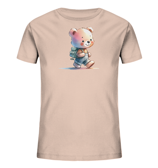 Onlineshop Shirts für Kinder - Das Bild zeigt ein hellrosa T-Shirt für Kinder mit einer niedlichen Comic-Bären-Grafik auf der Vorderseite. Der Bär ist in Overalls und mit einem Rucksack abgebildet, wie er lächelnd geht. Das Design hat einen Aquarell-Stil mit dezenten Farbschattierungen und zarten Farbstreifen darunter. Ein kleines Hashtag-Detail ergänzt die fröhliche Illustration.