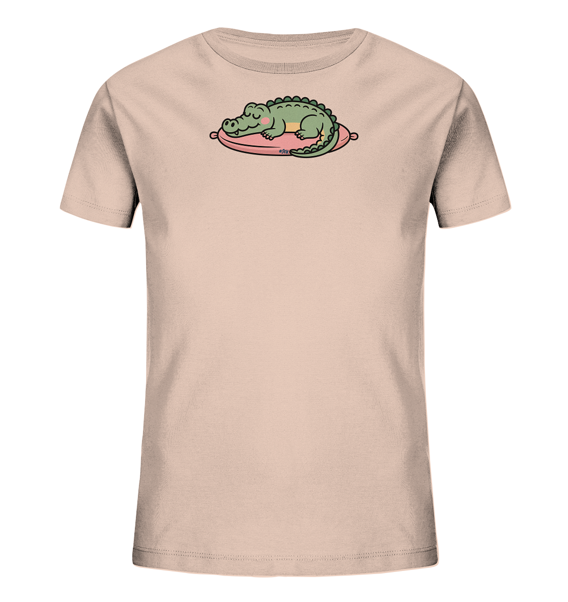 Onlineshop Shirts fuer Kinder - Das Bild zeigt ein hellbeiges Kinder-T-Shirt. Auf der Vorderseite ist ein schlafendes Krokodil abgebildet. Das gruene Krokodil liegt friedlich auf einem pinkfarbenen Kissen. Das Motiv verleiht dem Shirt einen ruhigen und verspielten Charakter.