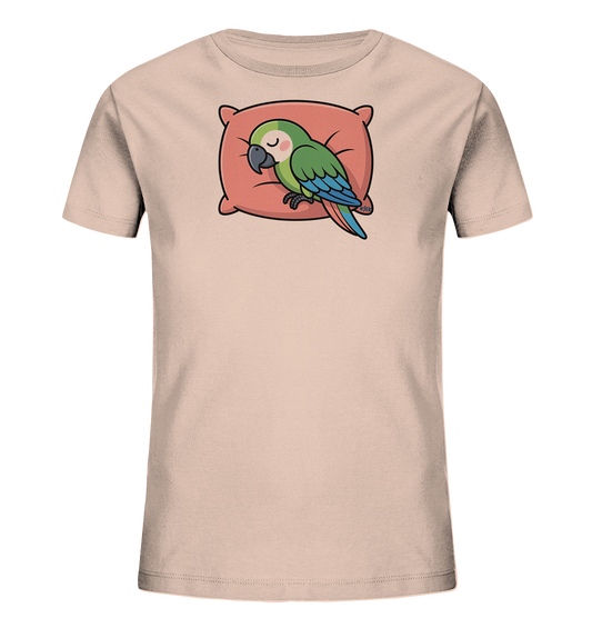 Onlineshop Shirts fuer Kinder - Das Bild zeigt ein hellbeiges Kinder-T-Shirt mit einem niedlichen Motiv eines schlafenden Papageis. Der gruene Papagei mit blauen Fluegeln liegt gemuetlich auf einem rosa-roten Kissen. Sein entspannter Ausdruck und die geschlossenen Augen vermitteln Ruhe. Das Design wirkt beruhigend und ist ideal fuer den Schlaf oder gemuetliche Stunden.