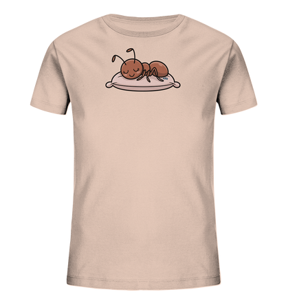 Onlineshop Shirts fuer Kinder - Das Bild zeigt ein hellbeiges Kinder-T-Shirt mit einem Frontdruck. Eine braune Cartoon-Ameise ist darauf zu sehen, die mit geschlossenen Augen auf einem pastellfarbenen Kissen liegt. Das Motiv stellt eine schlafende Ameise dar und ist in einem weichen, kindgerechten Stil gehalten. Die Illustration ist detailliert und farblich harmonisch auf das Shirt abgestimmt.