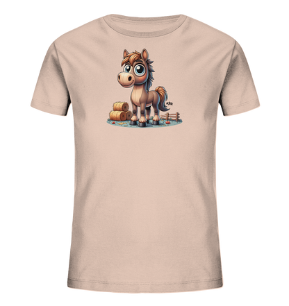 Onlineshop Shirts fuer Kinder - Das Bild zeigt ein hellrosafarbenes T-Shirt fuer Kinder mit einem suessen, cartoonhaften Pferdemotiv auf der Vorderseite. Das braune Pferd hat grosse, ausdrucksvolle blaue Augen und steht aufrecht. Umgeben ist es von Heuballen und einem Holzzaun, die eine Bauernhof-Szene darstellen. Kleine rote Punkte, eventuell Äpfel, liegen auf dem Boden verteilt.